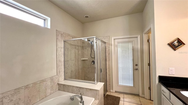 bathroom with a textured ceiling, vanity, tile patterned floors, and separate shower and tub