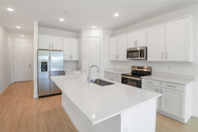 kitchen with a center island with sink, white cabinets, sink, and stainless steel appliances