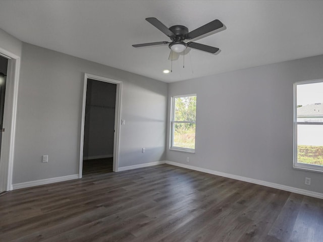 spare room with dark wood-type flooring, a healthy amount of sunlight, and ceiling fan