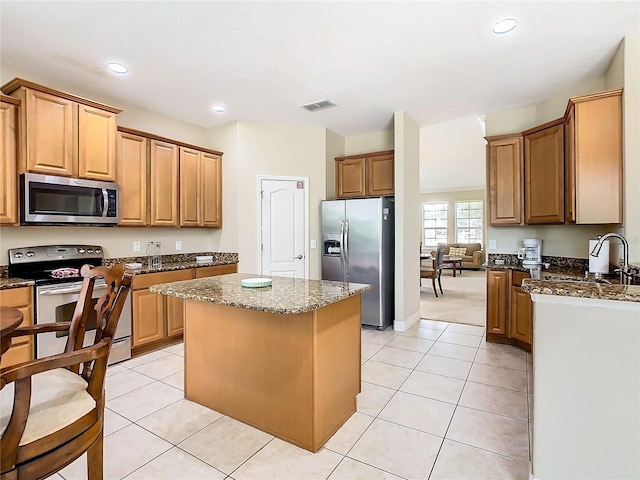 kitchen featuring appliances with stainless steel finishes, a center island, sink, and light tile patterned floors