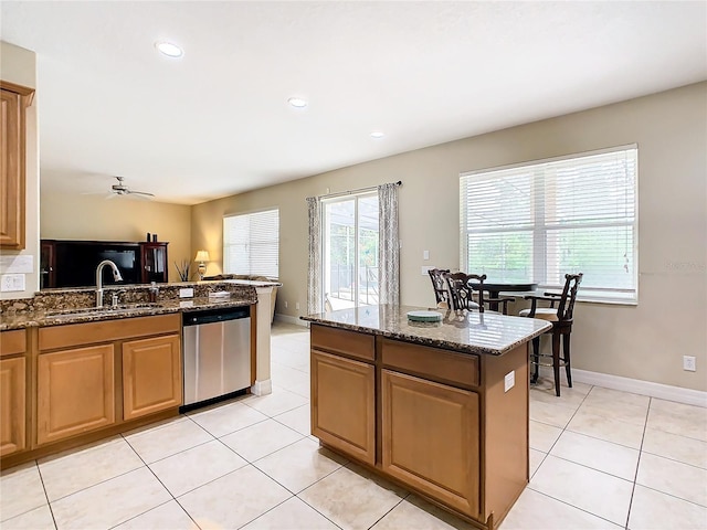 kitchen with sink, dishwasher, ceiling fan, dark stone counters, and light tile patterned floors