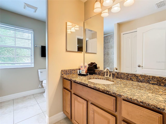 bathroom with toilet, vanity, and tile patterned flooring