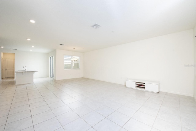 spare room featuring sink, light tile patterned floors, and a chandelier