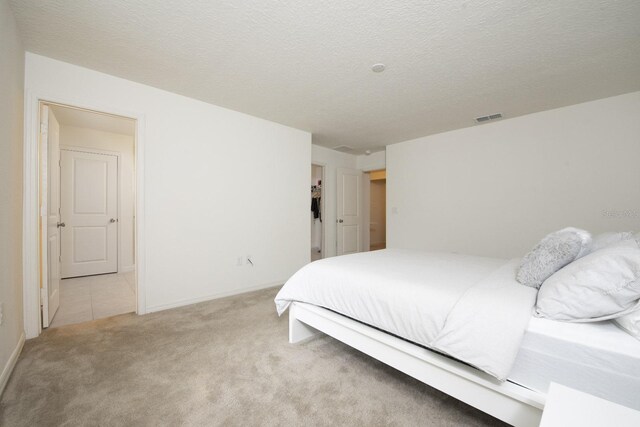 bedroom featuring light colored carpet and a textured ceiling