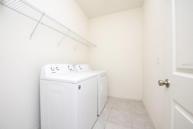 laundry area with laundry area, light tile patterned floors, baseboards, and washing machine and clothes dryer