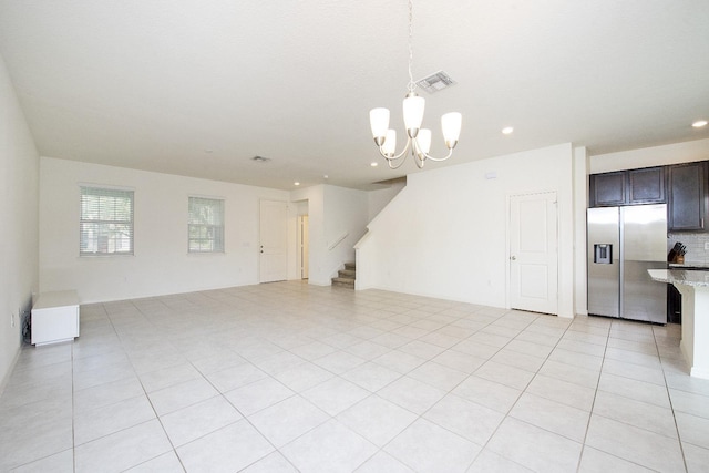 unfurnished living room with visible vents, a notable chandelier, recessed lighting, light tile patterned floors, and stairs