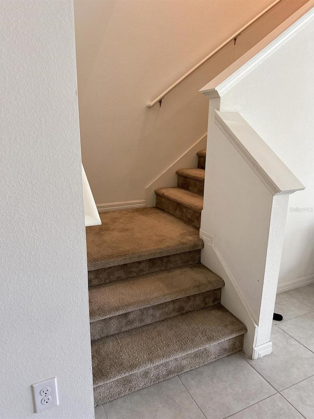 staircase featuring baseboards and tile patterned flooring