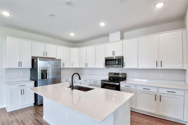 kitchen featuring a kitchen island with sink, white cabinetry, sink, and stainless steel appliances