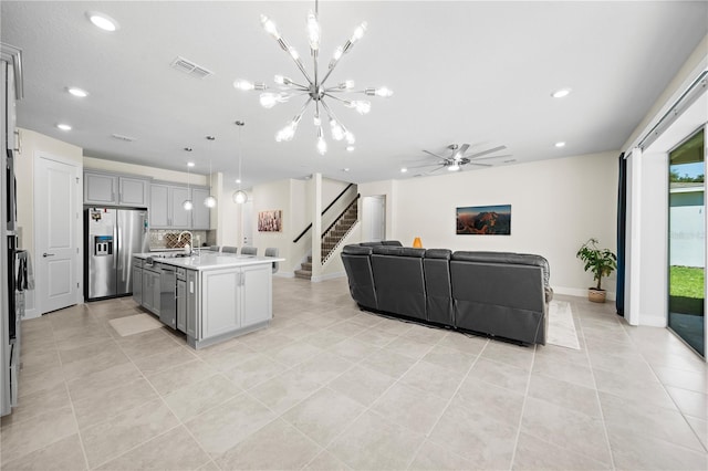 kitchen featuring light tile flooring, decorative light fixtures, gray cabinetry, a kitchen island with sink, and appliances with stainless steel finishes