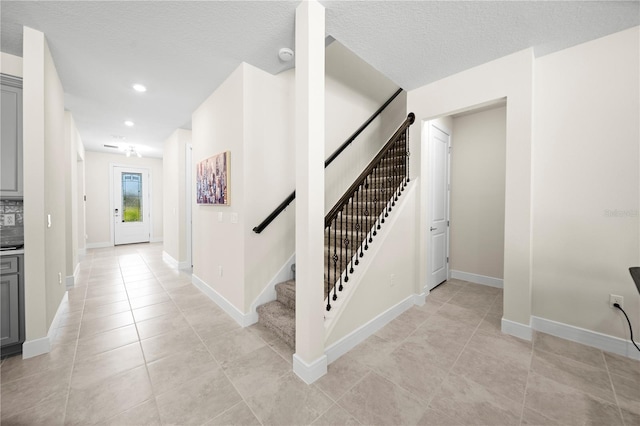 stairs featuring a textured ceiling and light tile floors