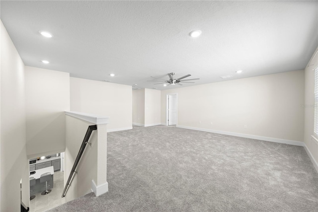 basement featuring ceiling fan and light colored carpet