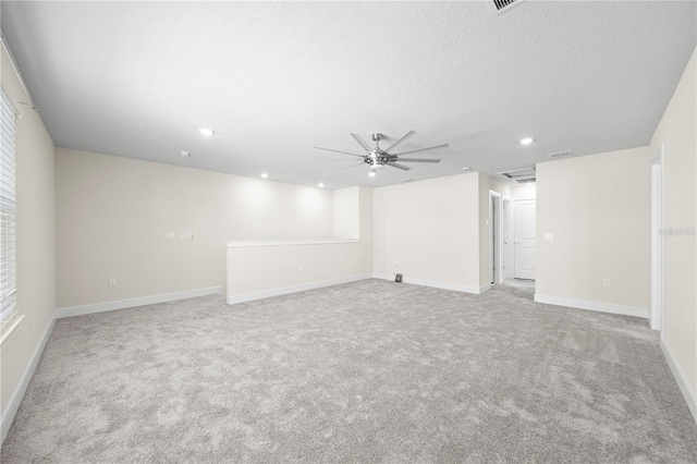 basement with a textured ceiling, ceiling fan, and light colored carpet