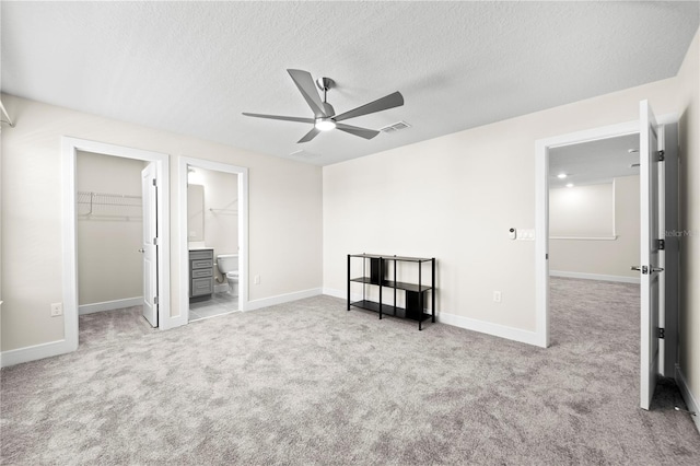 unfurnished bedroom with ceiling fan, a textured ceiling, light carpet, and a spacious closet