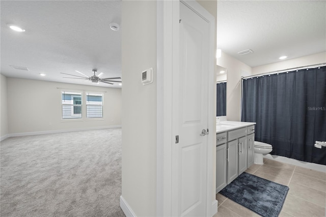 bathroom with a textured ceiling, ceiling fan, tile floors, vanity, and toilet