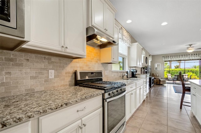 kitchen featuring decorative backsplash, gas stove, a healthy amount of sunlight, and white cabinetry