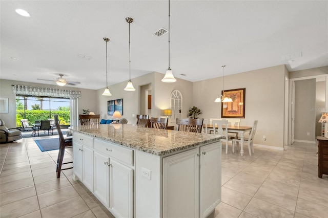 kitchen with ceiling fan, decorative light fixtures, a kitchen island, a kitchen bar, and white cabinetry