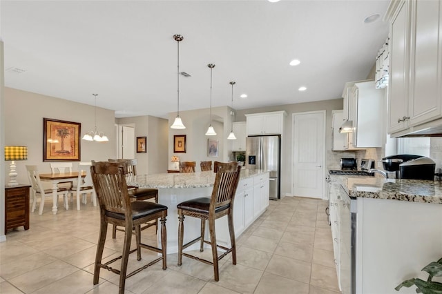 kitchen with a kitchen island, light stone counters, stainless steel refrigerator with ice dispenser, pendant lighting, and white cabinets