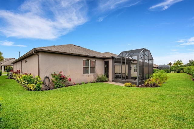 rear view of house with glass enclosure and a lawn