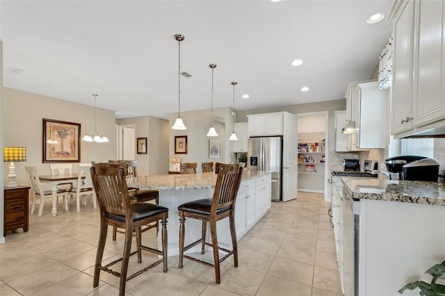 kitchen with white cabinets, hanging light fixtures, light stone countertops, a kitchen island, and stainless steel fridge with ice dispenser