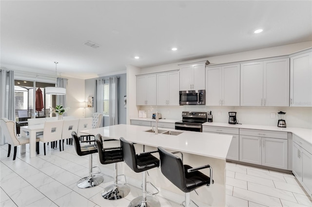 kitchen featuring a center island with sink, sink, stainless steel appliances, and a breakfast bar area