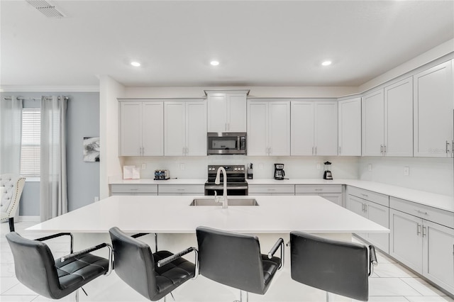 kitchen with a breakfast bar, sink, an island with sink, and appliances with stainless steel finishes