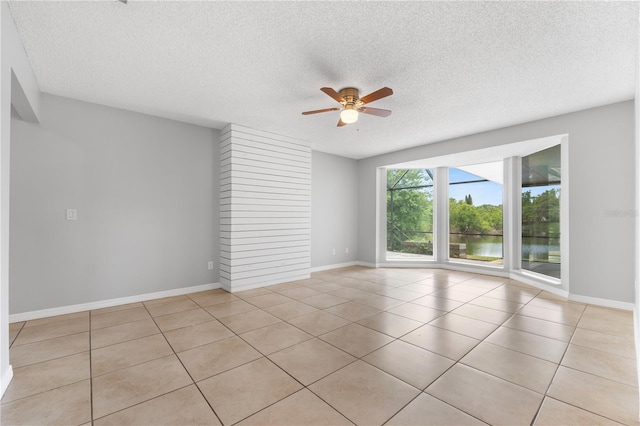 unfurnished room featuring a textured ceiling, light tile patterned flooring, ceiling fan, and a water view