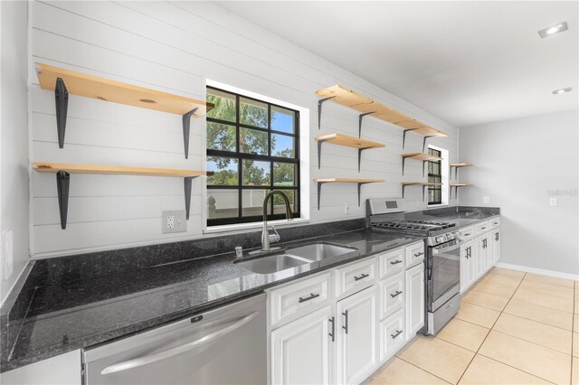 kitchen with white cabinetry, sink, dark stone counters, light tile patterned floors, and stainless steel appliances