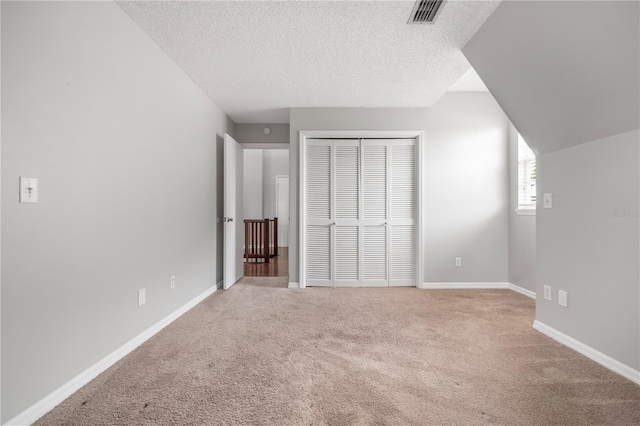 unfurnished bedroom featuring light carpet, a closet, and a textured ceiling