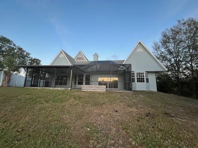 back of house featuring a yard and glass enclosure