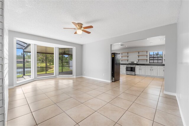 unfurnished living room with a water view, ceiling fan, a textured ceiling, and light tile patterned floors