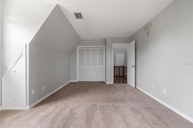 additional living space featuring light carpet and a textured ceiling