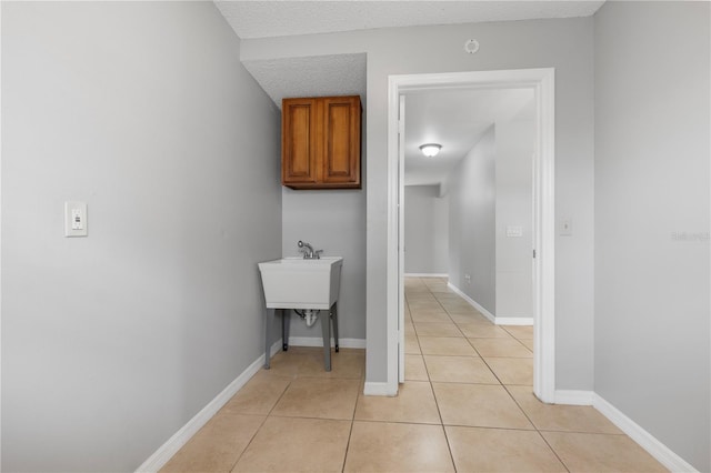 interior space with cabinets, a textured ceiling, and light tile patterned flooring