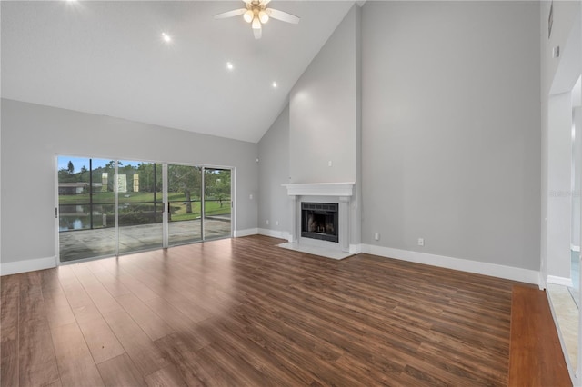 unfurnished living room featuring a tile fireplace, high vaulted ceiling, wood-type flooring, ceiling fan, and a water view