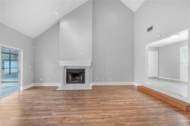 unfurnished living room featuring hardwood / wood-style floors, plenty of natural light, and high vaulted ceiling