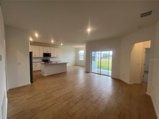 kitchen featuring stainless steel appliances, white cabinetry, and a kitchen island with sink