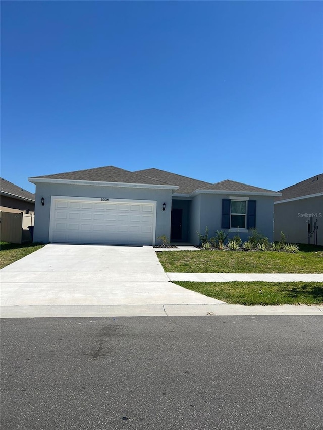 single story home featuring a garage and a front lawn