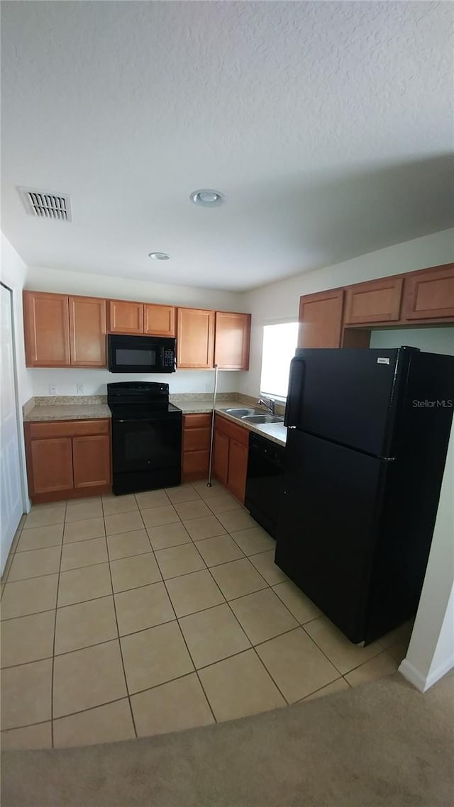 kitchen with sink, black appliances, and light tile floors