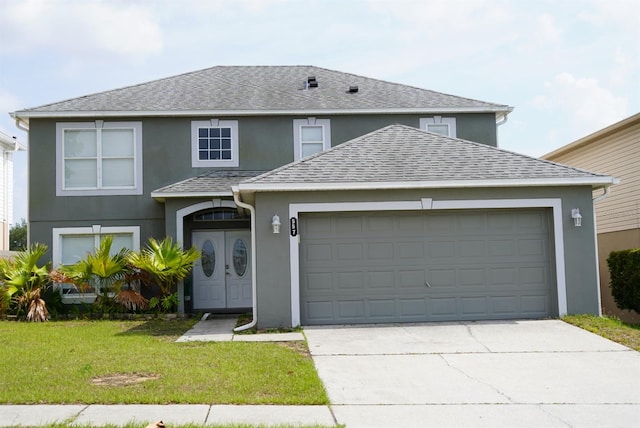 view of property with a garage and a front lawn