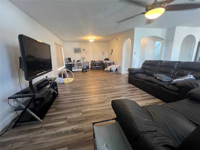 living room featuring hardwood / wood-style floors, ceiling fan, and a textured ceiling