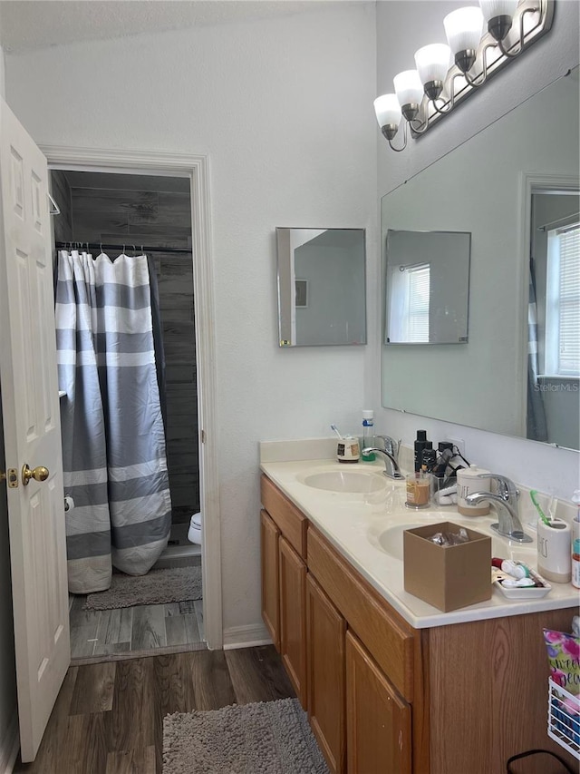 bathroom featuring large vanity, hardwood / wood-style flooring, toilet, and dual sinks