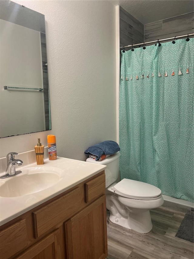 bathroom with a textured ceiling, wood-type flooring, toilet, and vanity