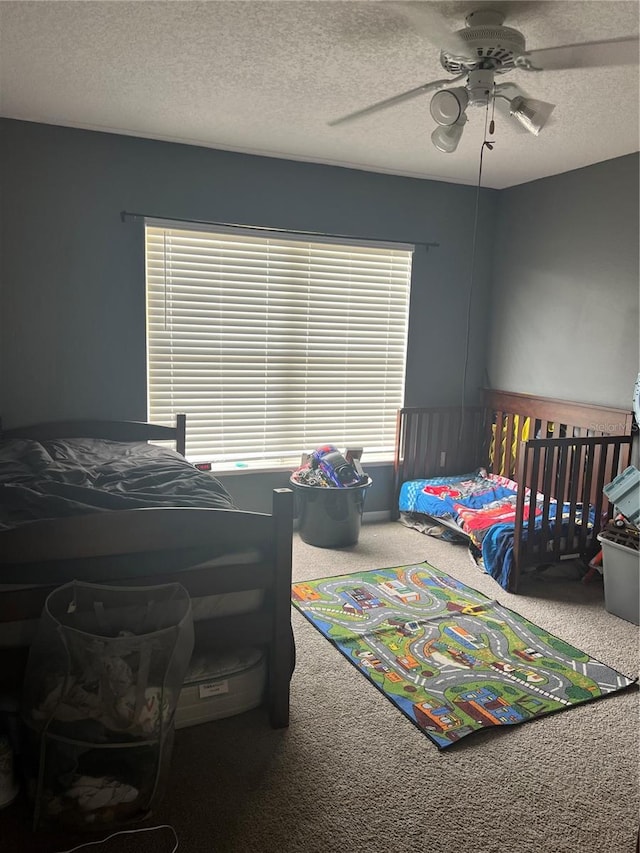 carpeted bedroom featuring ceiling fan and a textured ceiling