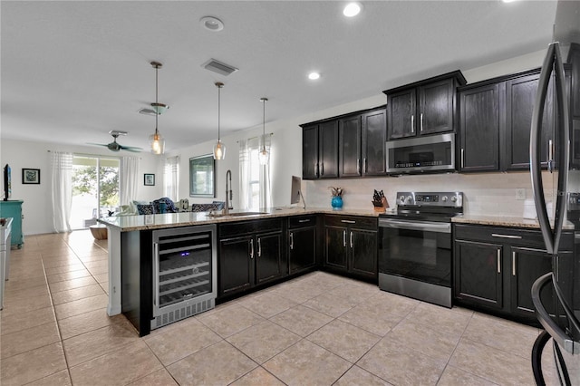 kitchen with ceiling fan, beverage cooler, stainless steel appliances, decorative light fixtures, and sink