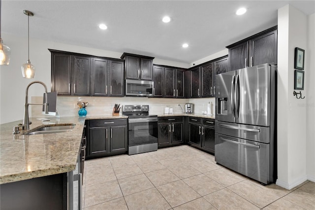 kitchen with stainless steel appliances, hanging light fixtures, light stone countertops, sink, and light tile floors