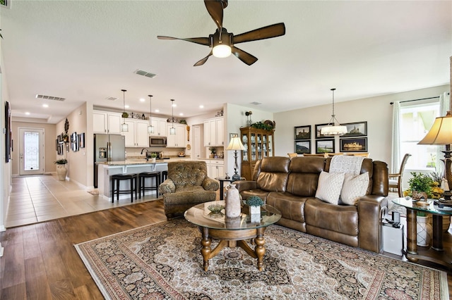 living room featuring light hardwood / wood-style floors, ceiling fan, and sink