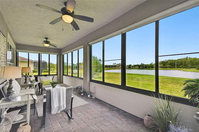 sunroom / solarium featuring ceiling fan, a healthy amount of sunlight, and a water view