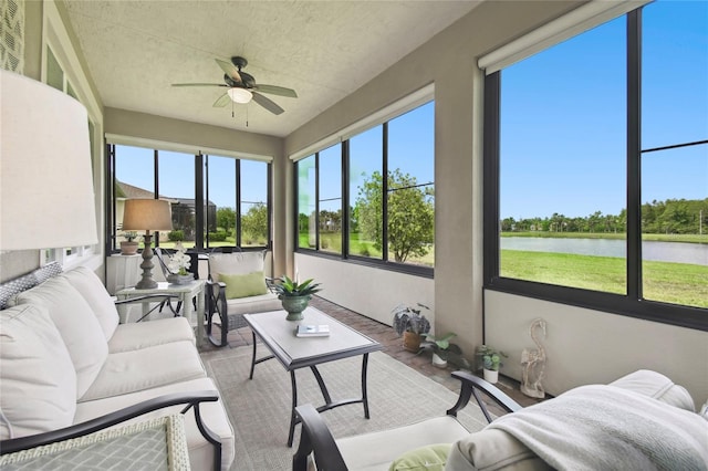 sunroom featuring ceiling fan and a water view