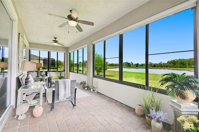 sunroom / solarium featuring a water view and ceiling fan