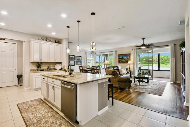 kitchen featuring a kitchen island with sink, sink, dishwasher, and plenty of natural light