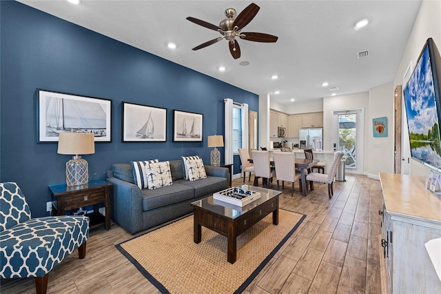 living room with ceiling fan and light hardwood / wood-style flooring